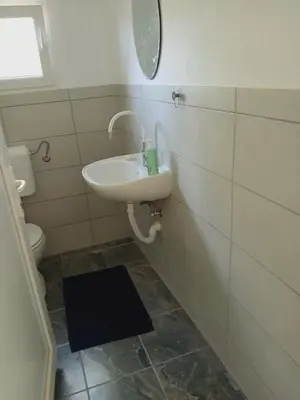 a bathroom with a sink and a mirror and a toilet at Log Cabins Jovicic in Bosanska Dubica