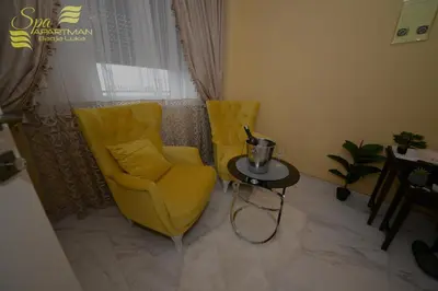 a living room with a yellow chair and a table at Spa Apartman Banja Luka in Banja Luka