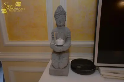 a statue of a statue holding a candle on a desk at Spa Apartman Banja Luka in Banja Luka