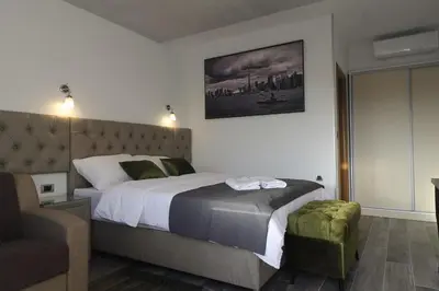 a bedroom with a large bed and a chair at Motel Atos Bungalovi in Nova Topola