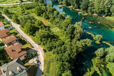 an aerial view of a river with a house and trees at apartment HOME in Bihać