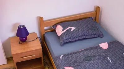 a small bed with a purple pillow and a lamp at apartment HOME in Bihać