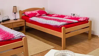 a bedroom with two beds with red sheets and a table at apartment HOME in Bihać