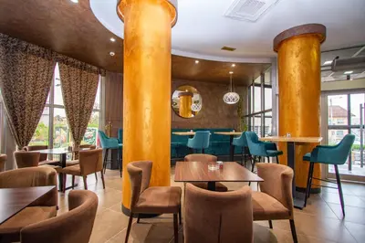 a restaurant with yellow columns and tables and chairs at Hotel Grand in Banja Luka
