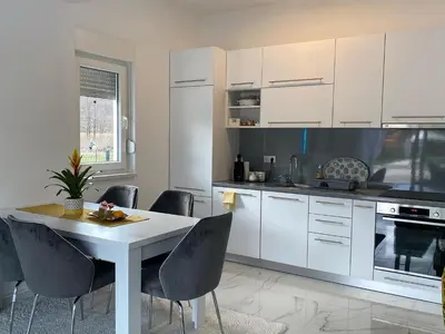 a kitchen with white cabinets and a table and chairs at River Luxury House in Bihać