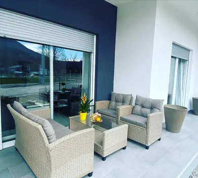a patio with wicker chairs and a glass table at River Luxury House in Bihać