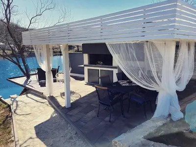 a white pergola with a table and chairs on a deck at River Luxury House in Bihać
