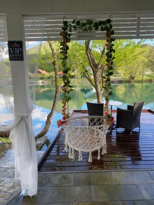 a patio with a table and chairs on a deck with flowers at River Luxury House in Bihać