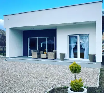 a white house with two couches and a plant at River Luxury House in Bihać