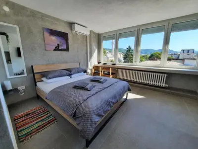 a bedroom with a bed and a large window at Apartman Tvrdjava in Banja Luka