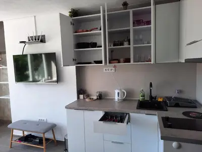 a kitchen with white cabinets and a sink and a stool at Apartman Tvrdjava in Banja Luka