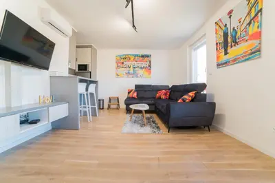 a living room with a black couch and a kitchen at Apartman EpiCent in Tuzla