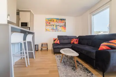 a living room with a black couch and a kitchen at Apartman EpiCent in Tuzla