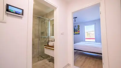 a bathroom with a shower and a bed and a mirror at Apartman EpiCent in Tuzla