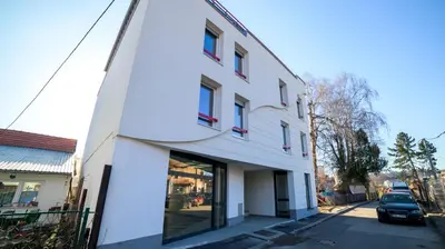 a white building with red windows on a street at Apartman EpiCent in Tuzla