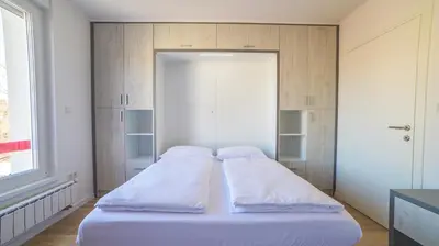 a bed with white sheets and pillows in a room at Apartman EpiCent in Tuzla
