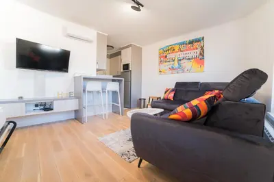a living room with a black couch and a flat screen tv at Apartman EpiCent in Tuzla