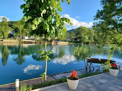 a view of a lake with a bench and trees at Una Luxury Home in Bihać