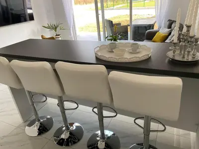 a kitchen with a black counter and white chairs at Una Luxury Home in Bihać