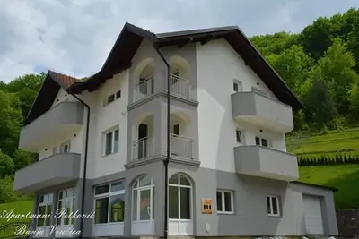 a large white building with balconies and trees at APARTMANI PETKOVIC in Teslić