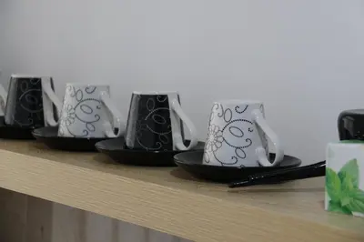 a row of coffee mugs sitting on a shelf at Royal City Apartments in Jajce