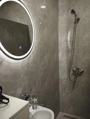a bathroom with a shower and a sink and a mirror at Apartman 053 in Doboj
