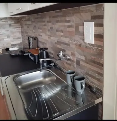 a stainless steel kitchen sink with two cups on a counter at Apartman 053 in Doboj