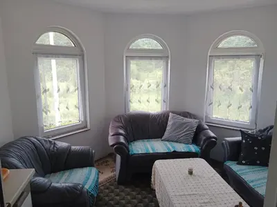 a living room with two couches and two windows at Vila Anđelija in Velika Kladuša