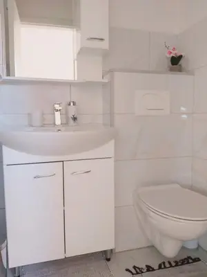 a white bathroom with a sink and a toilet at apartman UNO in Jajce