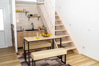 a kitchen with a table and a staircase in a room at apartman UNO in Jajce