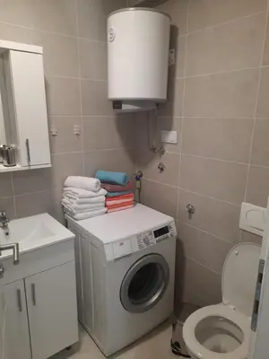 a bathroom with a washing machine and a sink at Apartman Tami in Doboj