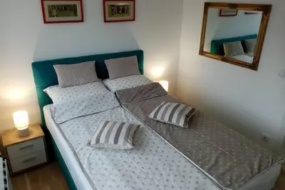 a bed with two pillows and a mirror on the wall at Stan, Apartman Eleven-Elf Tuzla centar, NOVO in Tuzla