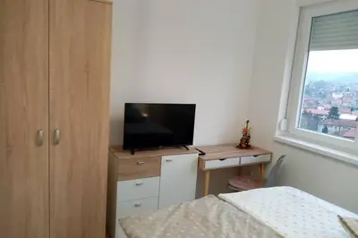 a bedroom with a bed and a television on a desk at Stan, Apartman Eleven-Elf Tuzla centar, NOVO in Tuzla