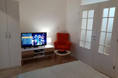 a living room with a television and a red chair at Stan, Apartman Eleven-Elf Tuzla centar, NOVO in Tuzla