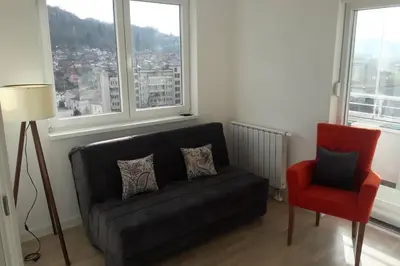a living room with a black couch and a red chair at Stan, Apartman Eleven-Elf Tuzla centar, NOVO in Tuzla