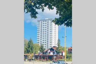 a tall white building in front of a playground at Stan, Apartman Eleven-Elf Tuzla centar, NOVO in Tuzla