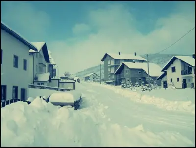 a street covered in snow with buildings and houses at Apartments Marevic in Kupres