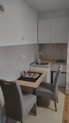 a kitchen with a table and two chairs and a sink at M&I Apartment in Doboj