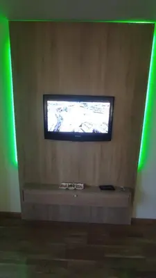 a television on a wall in a room with green lights at M&I Apartment in Doboj
