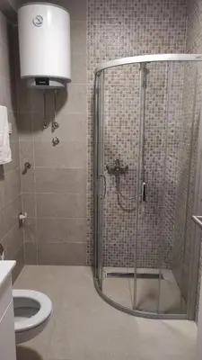 a bathroom with a shower with a toilet and a sink at M&I Apartment in Doboj