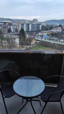 a table and chairs on a balcony with a view of a city at M&I Apartment in Doboj