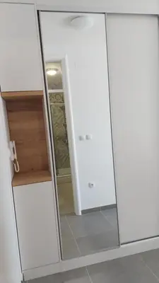 a closet with white cabinets and a glass door at Apartman Green Lux in Banja Luka