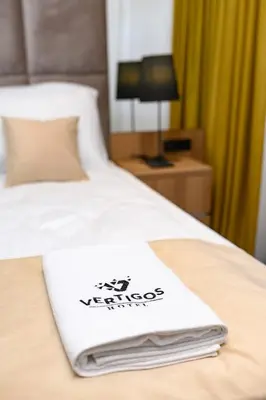 a hotel room with a white towel on a bed at Hotel Vertigos in Tuzla