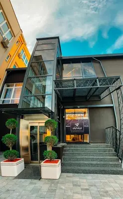 a building with stairs and potted plants in front of it at Hotel Vertigos in Tuzla