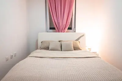 a bedroom with a bed with a pink curtain at Apartman Royal 2 in Doboj
