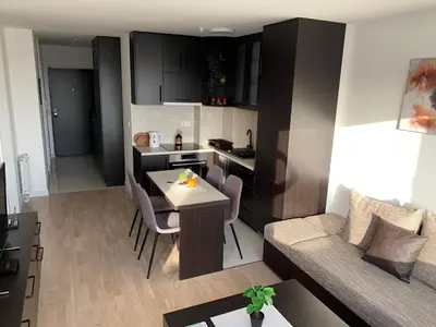a kitchen and a living room with a table and a couch at Apartman Tuzla - Blizu Panonskih jezera i centra grada in Tuzla