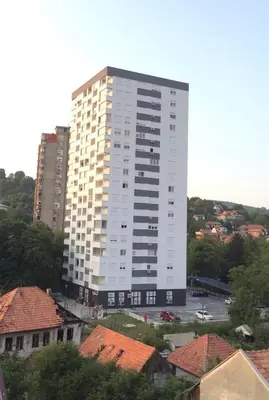 a tall white building in a city with roofs at Apartman Tuzla - Blizu Panonskih jezera i centra grada in Tuzla