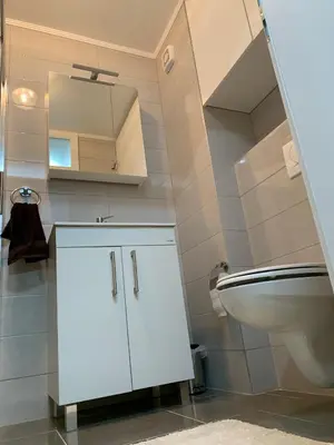 a white bathroom with a sink and a toilet at Apartman Tuzla - Blizu Panonskih jezera i centra grada in Tuzla