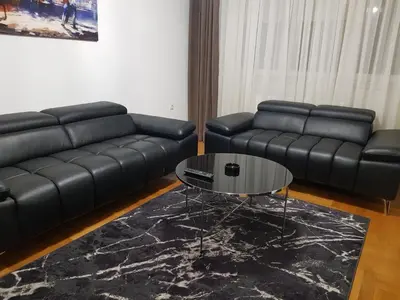 a living room with a black leather couch and a table at Apartman Casa Banja Luka in Banja Luka