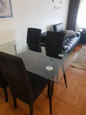 a glass table with black chairs and a couch at Apartman Casa Banja Luka in Banja Luka